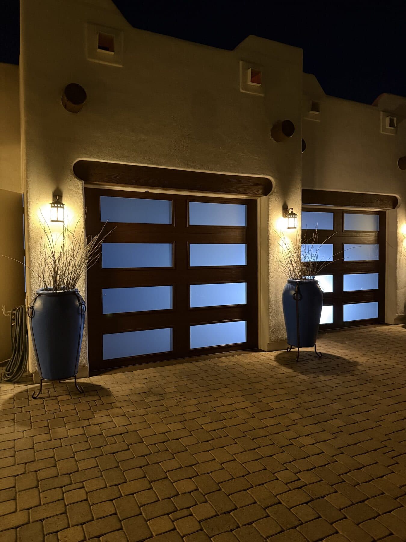 Garage Door Replacement Phoenix Modern glass-and-wood garage doors glowing at dusk on a Phoenix, AZ home installed by Desert Spring