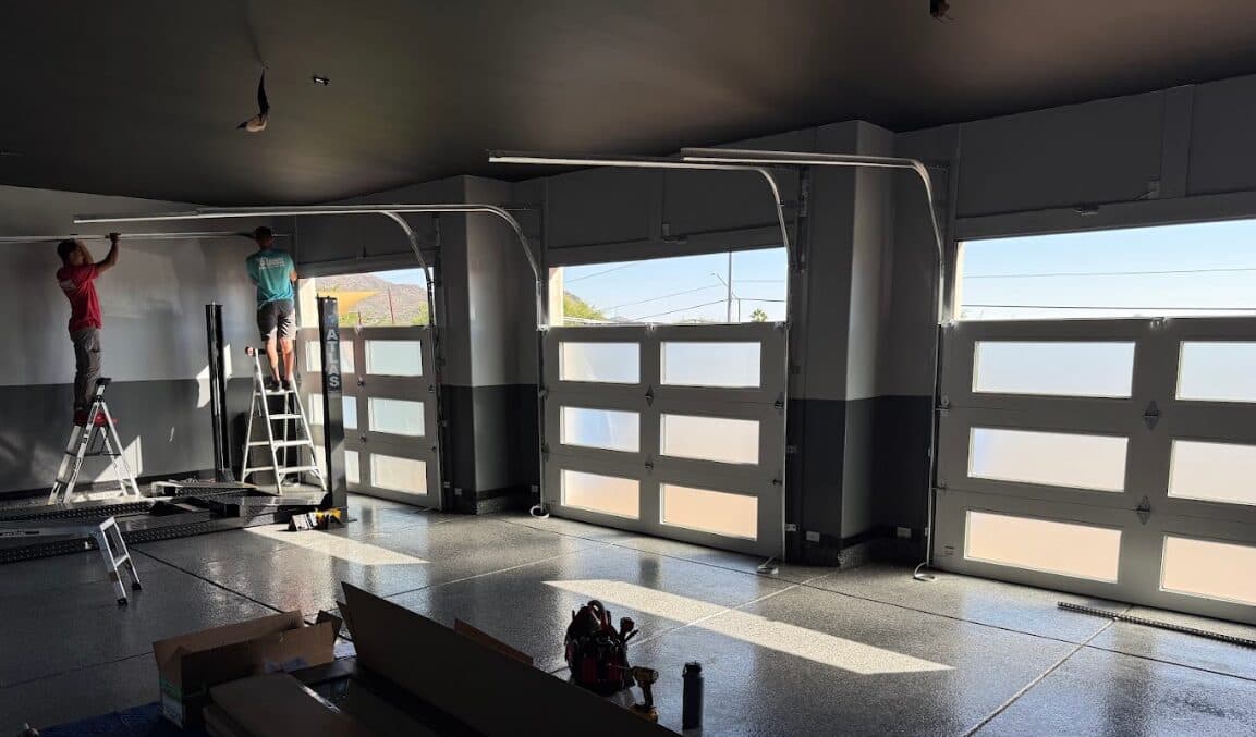 Garage Door Spring Repair Phoenix Desert Spring technicians installing modern glass-and-wood garage doors at a Phoenix, AZ home