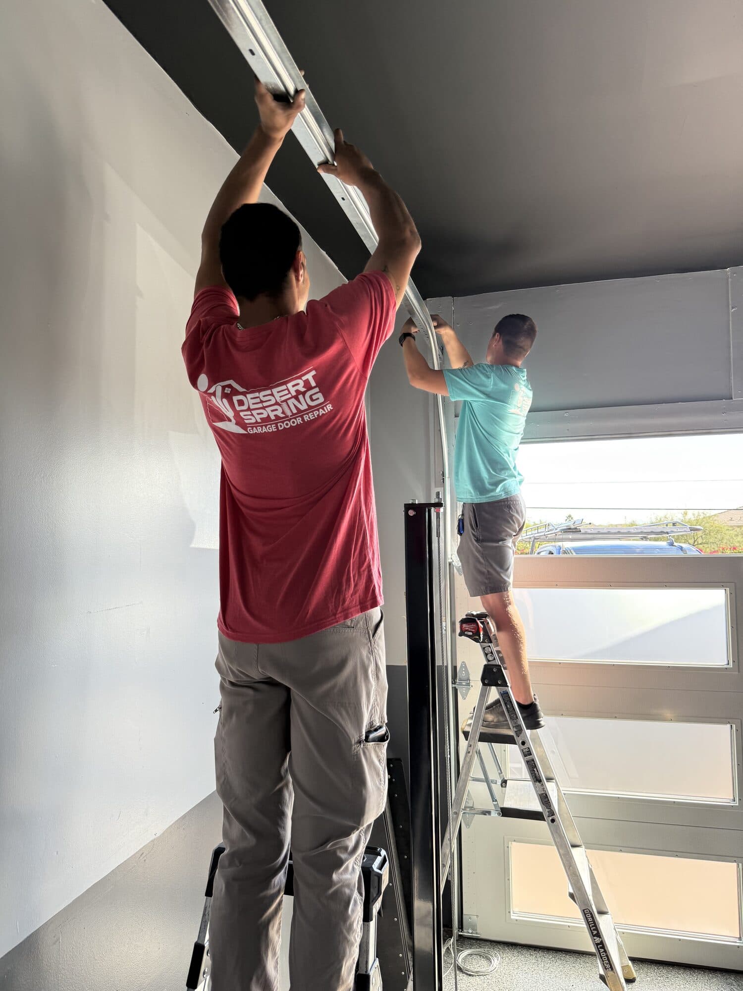 Garage Door Installation Phoenix Desert Spring technicians installing a modern glass garage door in a Phoenix, AZ garage